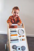 Petit garçon qui joue avec le chariot d’activités bébé en bois avec jeux d’éveil