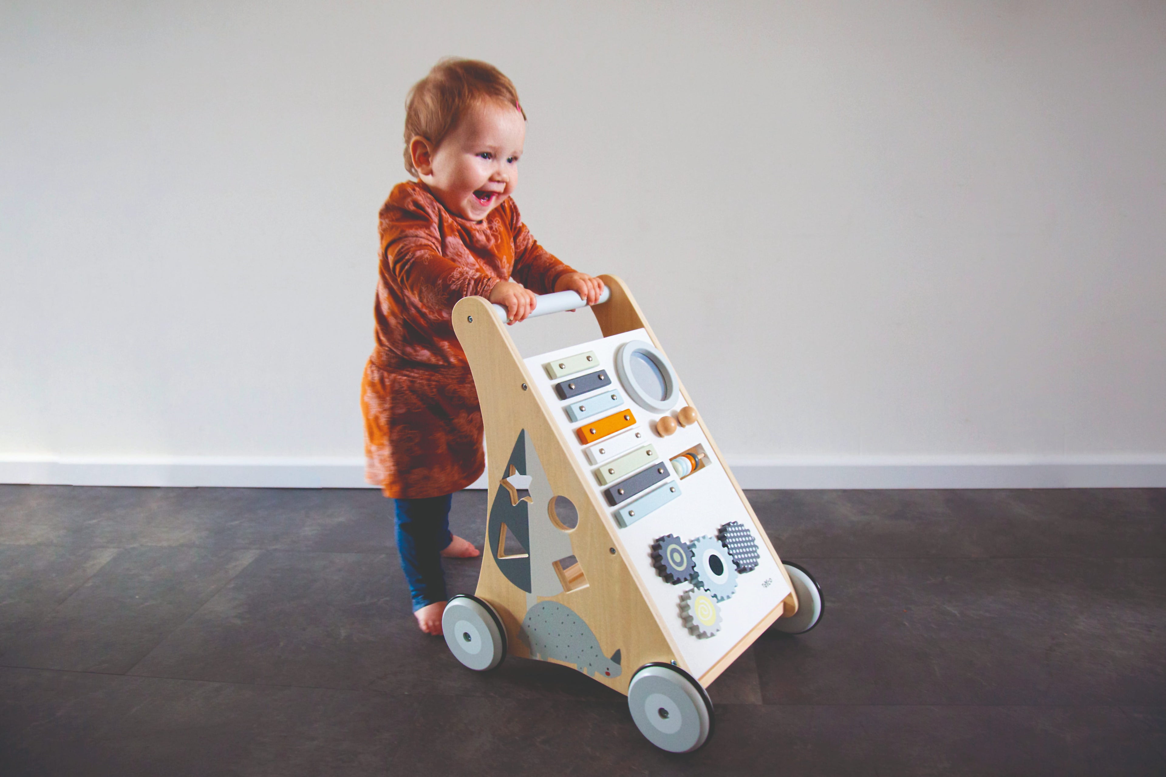 Petit garçon qui marche avec le chariot d’activités bébé en bois avec jeux d’éveil