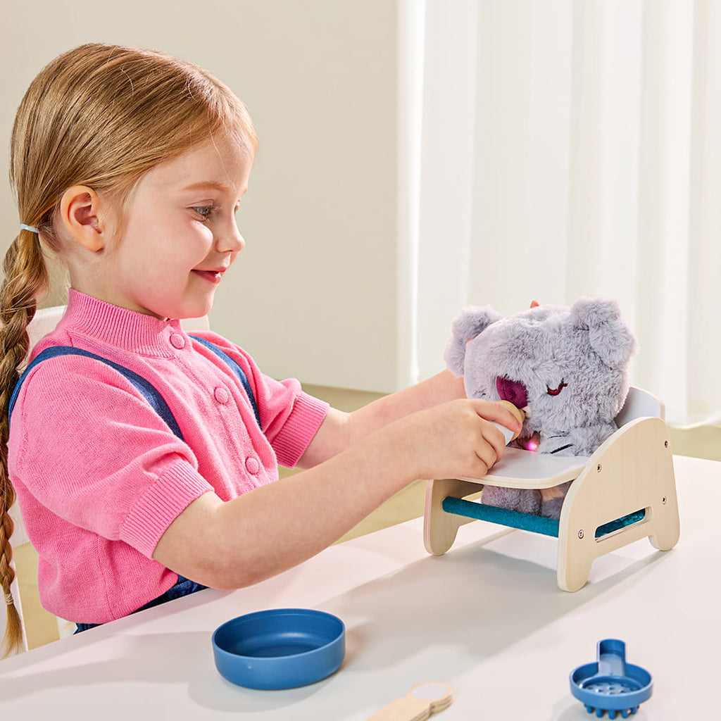 Petite fille donnant le biberon à la peluche interactive bébé koala avec cœur lumineux