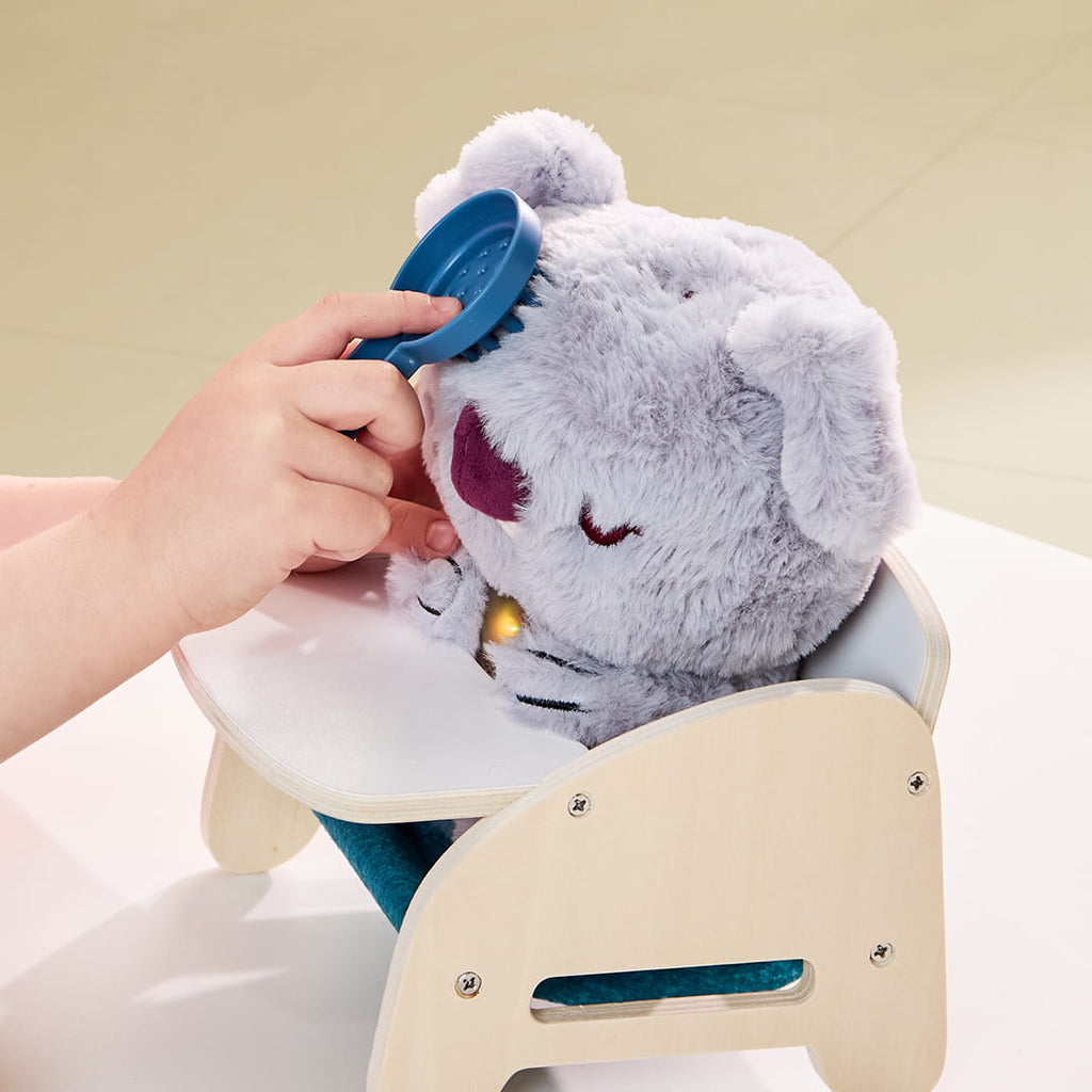 Petite fille peignant la peluche interactive bébé koala avec cœur lumineux