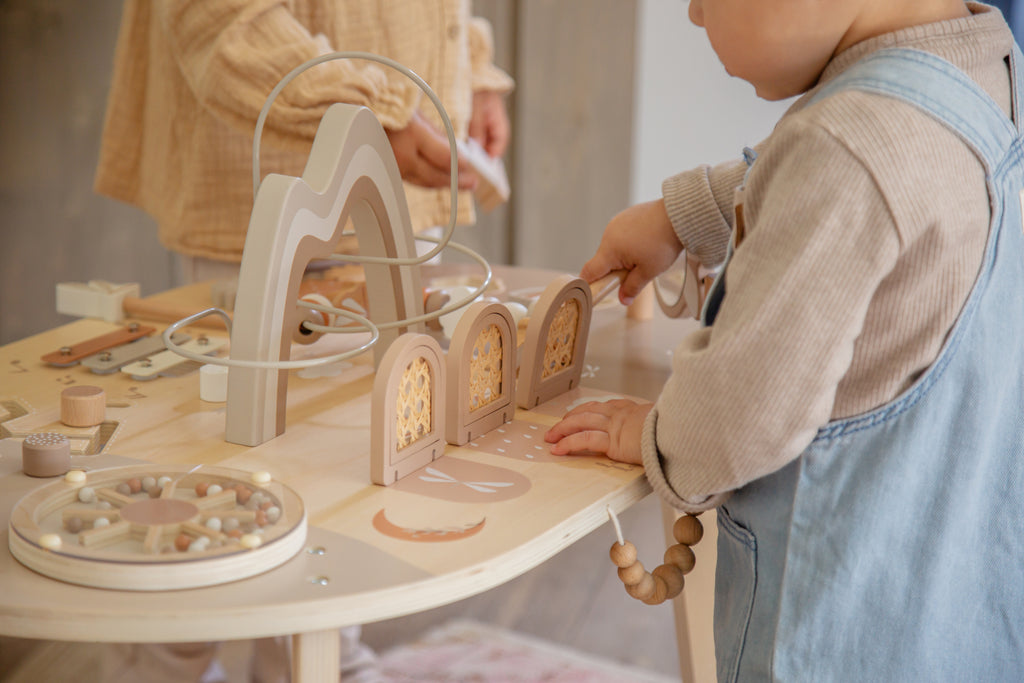 Enfant qui joue avec la table d’activité enfant en bois avec jeux interactifs