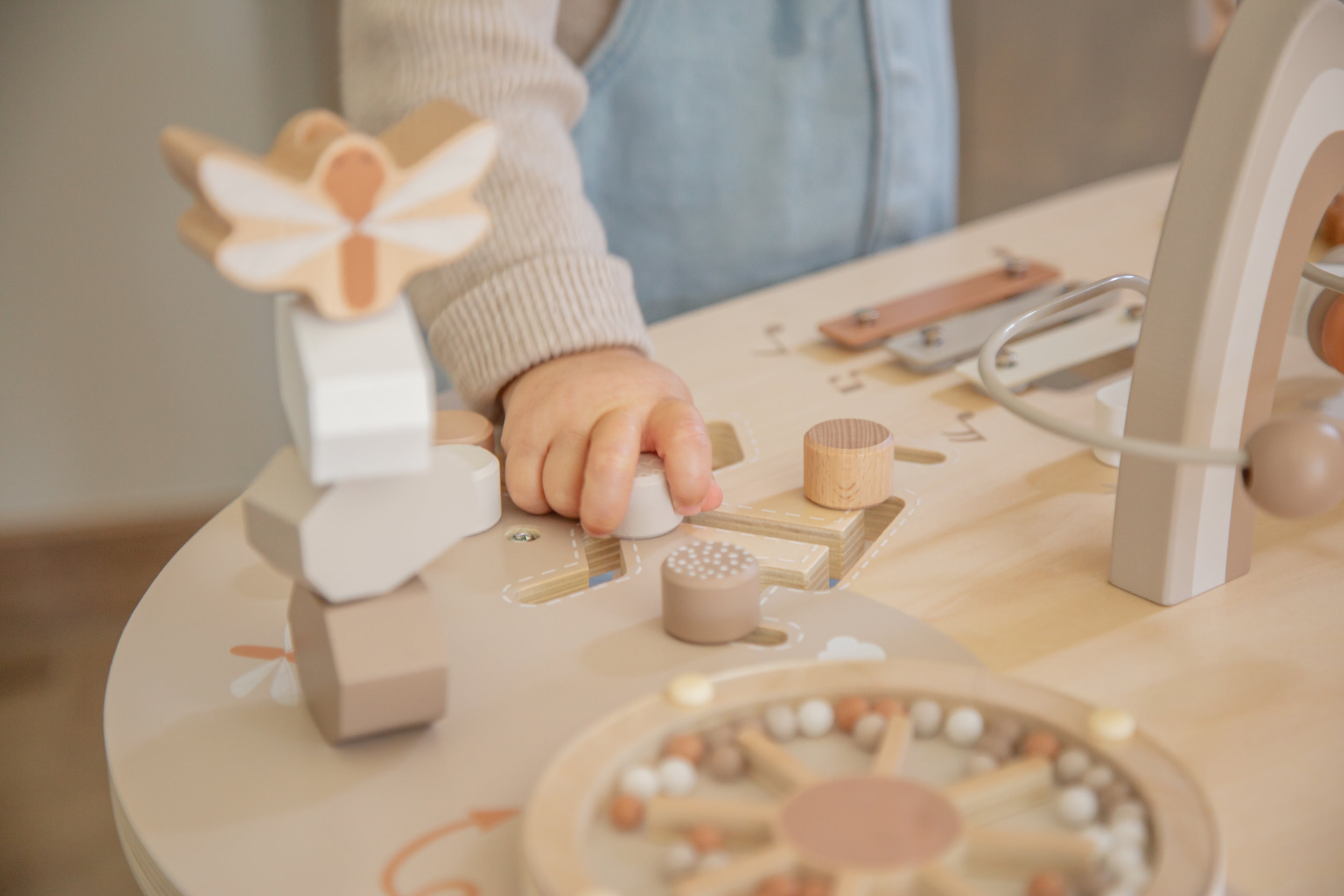 Enfant qui interagit avec un rouage de la table d’activité enfant en bois avec jeux interactifs