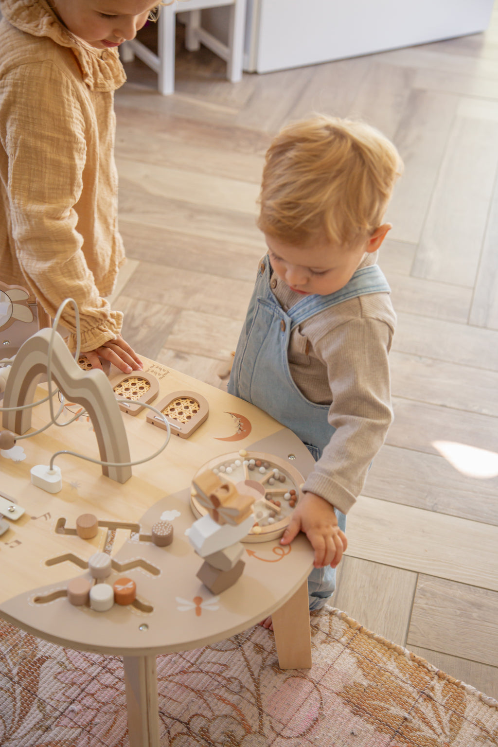 Deux enfants jouant avec la roulette de la table d’activité enfant en bois avec jeux interactifs