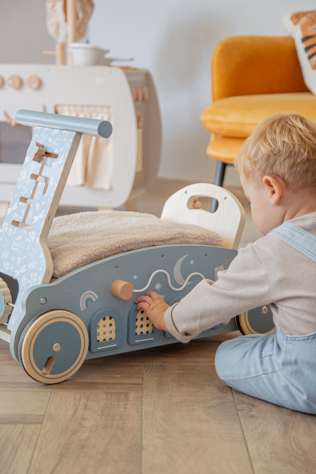 Petit garçon assis qui joue avec la voiture en bois 3 en 1 bébé marcheur bascule et porteur bleu