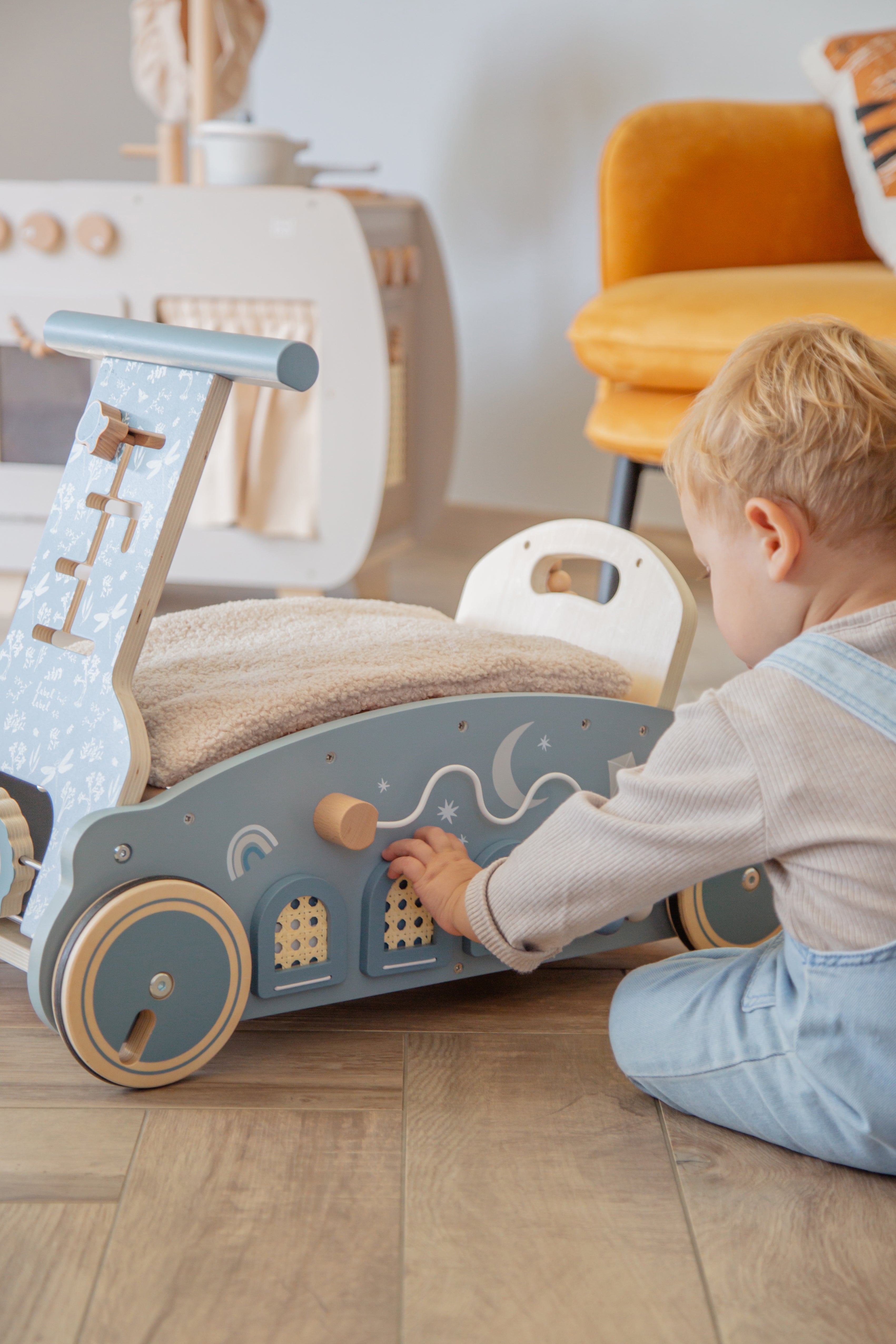 Petit garçon assis qui joue avec la voiture en bois 3 en 1 bébé marcheur bascule et porteur bleu